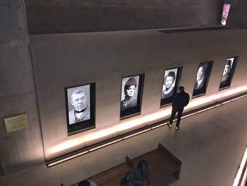 A man observes a wall with photographs of different people at the exhibition at the National Museum of African American History and Culture
